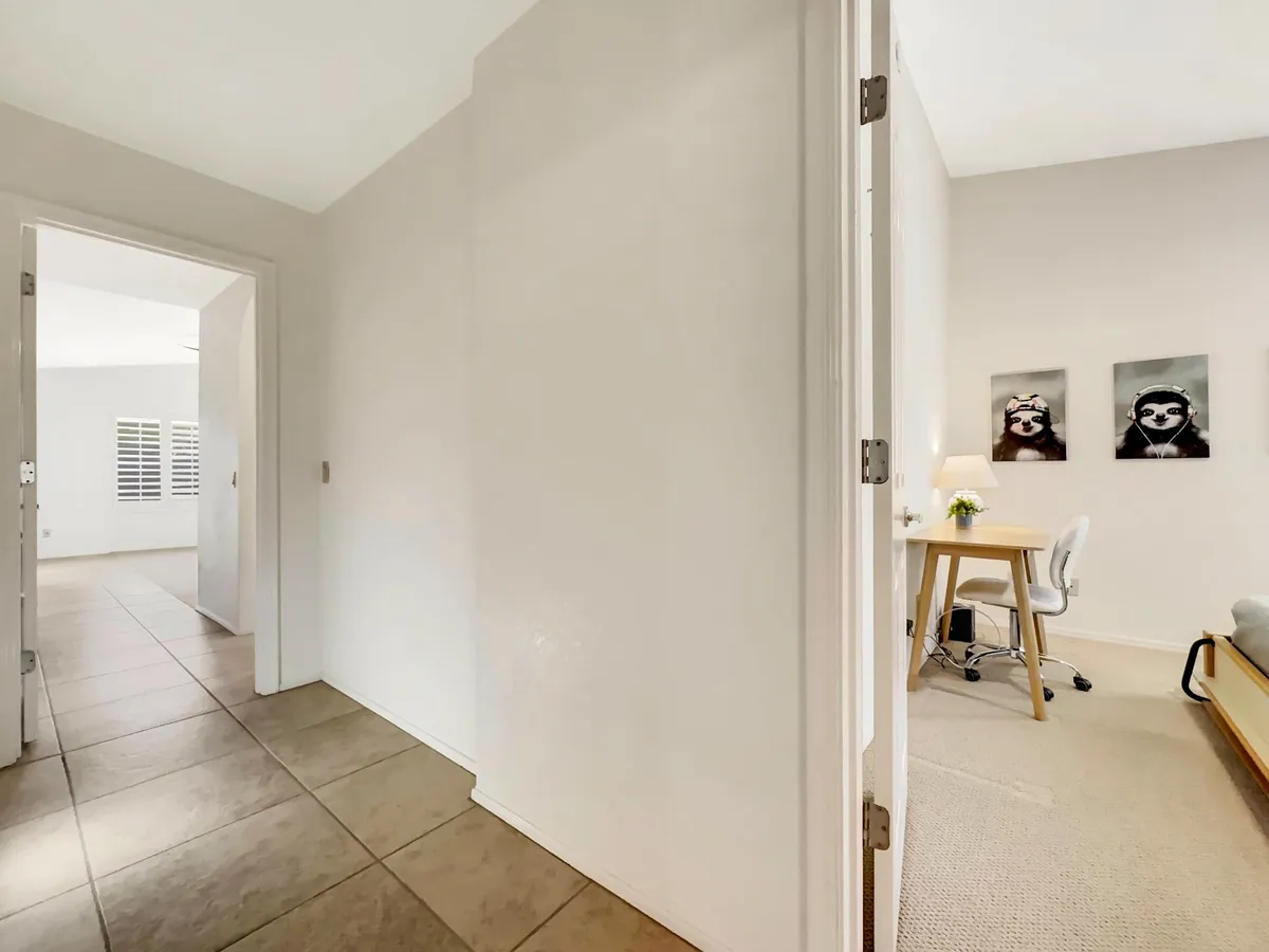 A calm, productive workspace featuring a desk and chair, complemented by soft lighting and elegant wall art. The setting feels peaceful and removed from distractions, ideal for focused remote work. The lamp with a flower adds a homely touch.