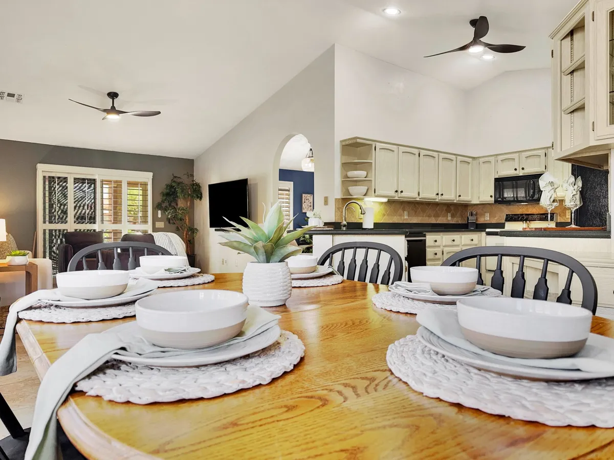 An inviting dining table set next to the kitchen area, adorned with a potted plant. The setup is ready for family meals, celebrations, or casual gatherings.