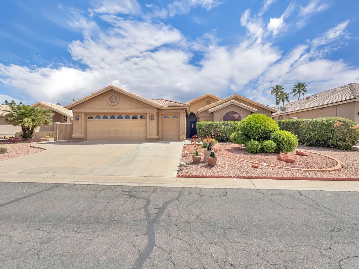 A broader perspective of the property's exterior, showcasing lush front yard landscaping, the entrance, and the driveway. The serene setting suggests spaces to enjoy the outdoors, relax with coffee, or socialize as the sun sets.